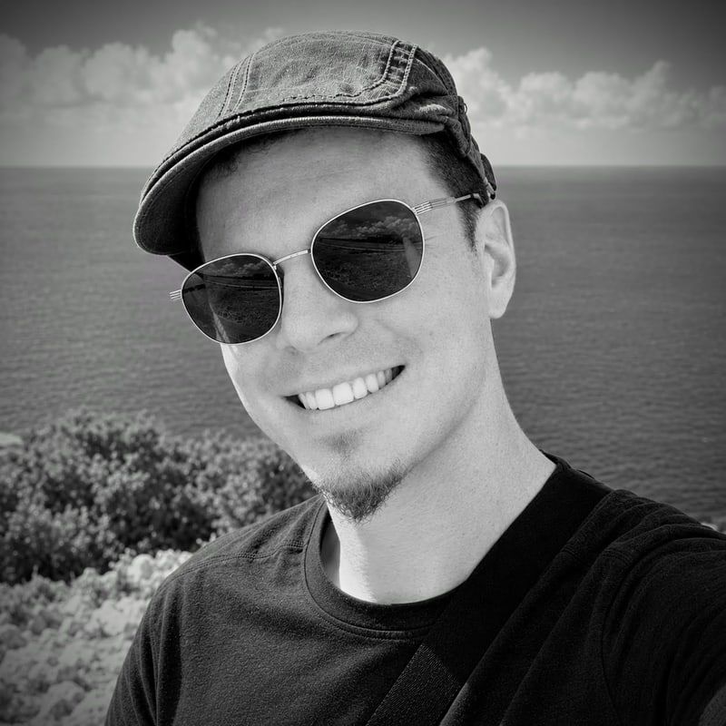 Pierre, le créateur d’EventSlide, en photo noir et blanc : il sourit, casquette et lunettes de soleil, devant la mer.
